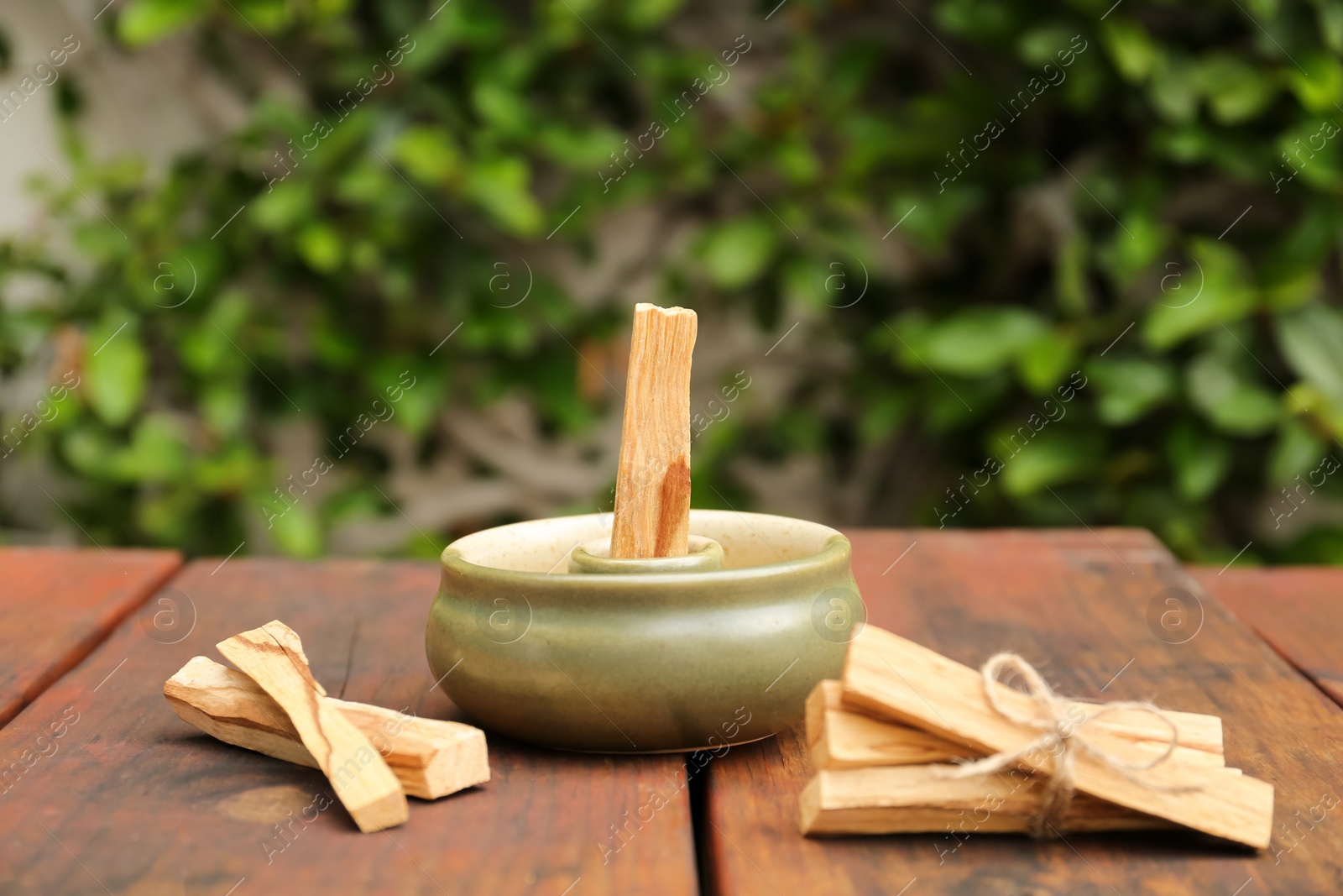 Photo of Palo Santo (holy wood) sticks and holder on wooden table outdoors