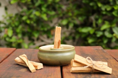 Photo of Palo Santo (holy wood) sticks and holder on wooden table outdoors