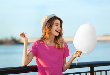 Photo of Happy young woman with cotton candy on waterfront