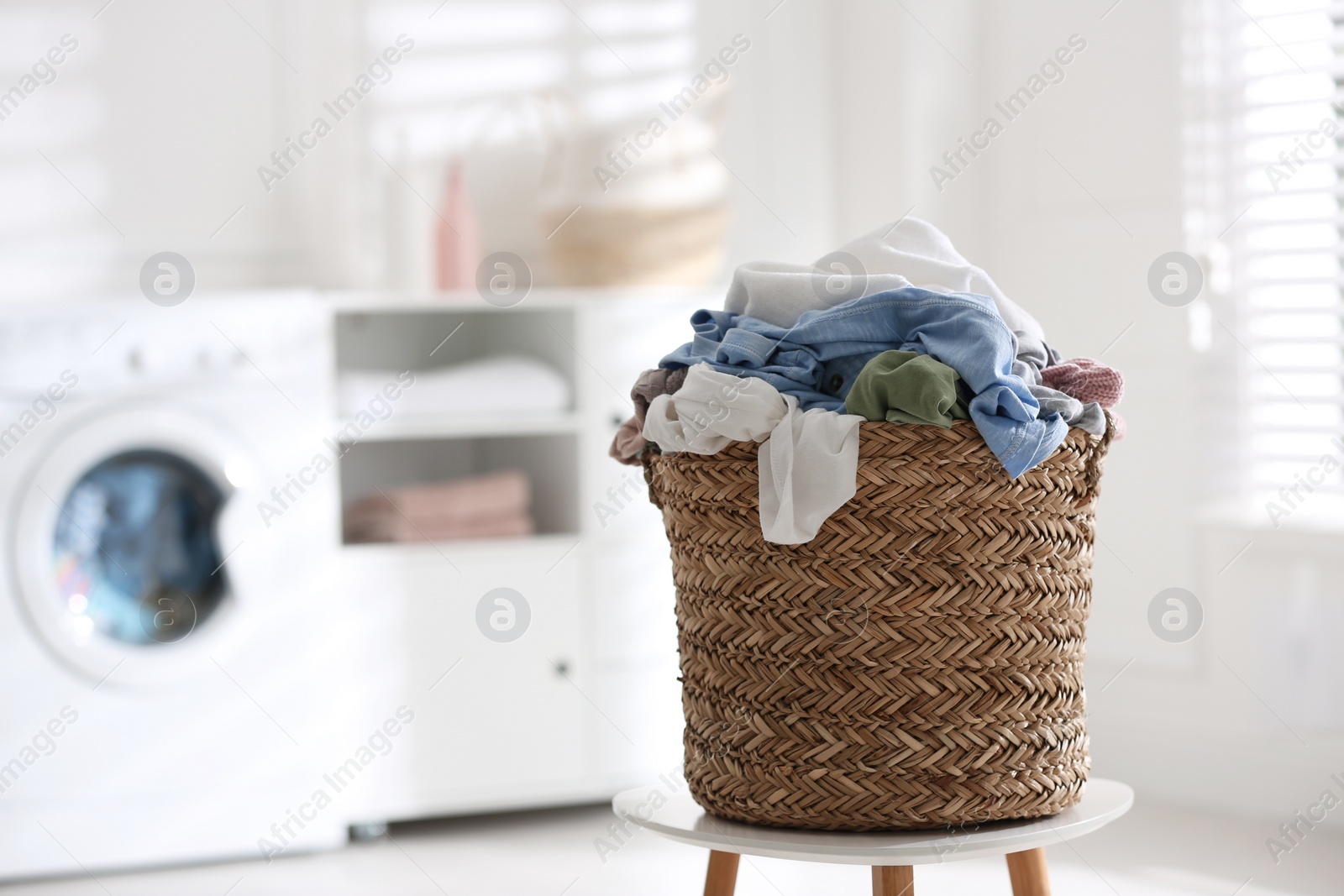 Photo of Wicker basket with dirty laundry indoors, space for text