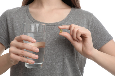 Photo of Young woman with vitamin pill and glass of water on white background, closeup