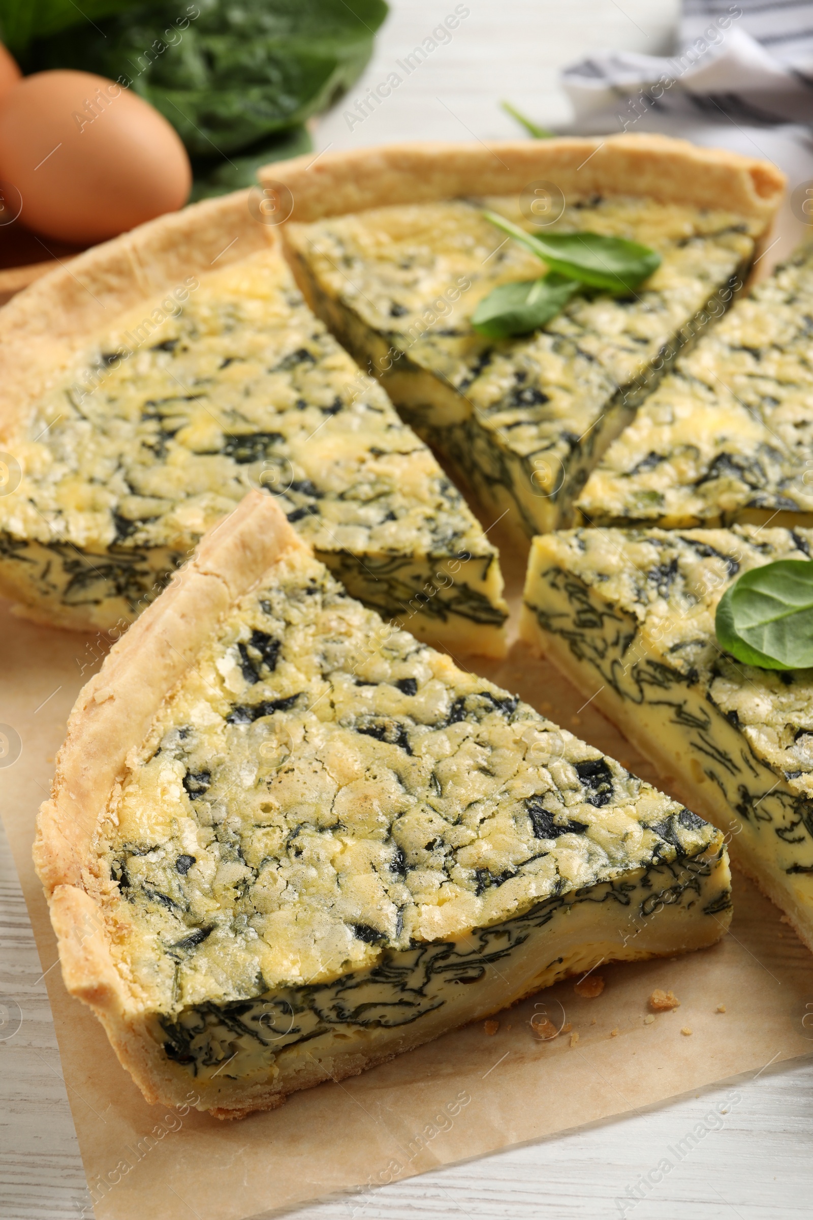 Photo of Cut delicious spinach pie on white wooden table, closeup