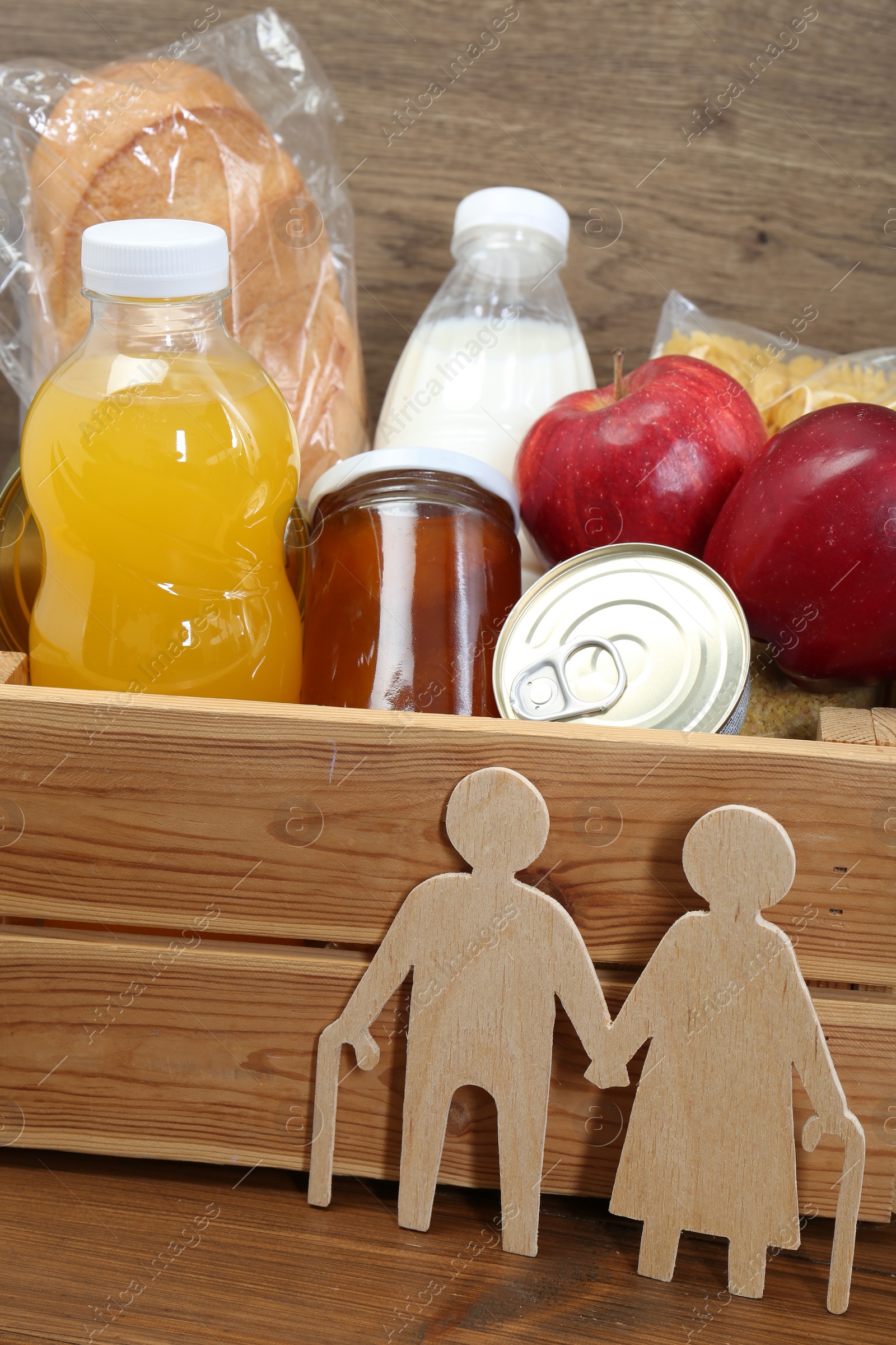 Photo of Humanitarian aid for elderly people. Different donation food products and figures of senior couple on wooden table, closeup