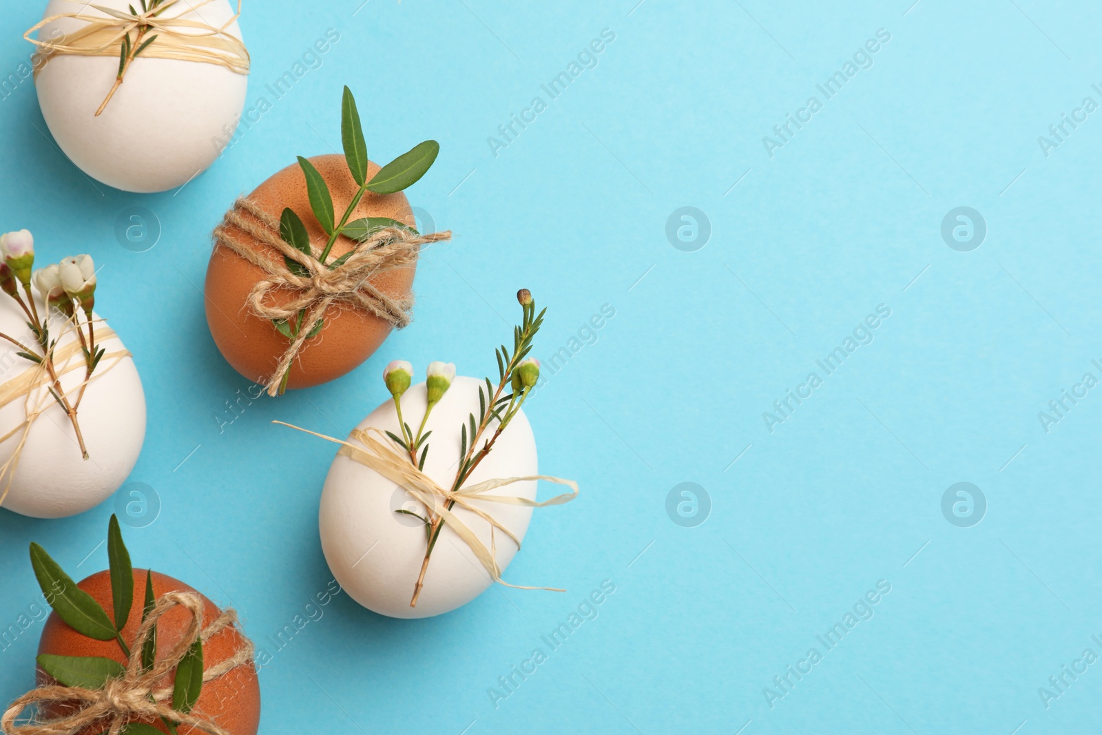 Photo of Festively decorated chicken eggs on light blue background, flat lay with space for text. Happy Easter