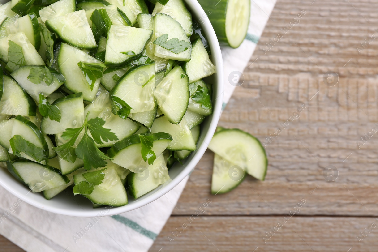 Photo of Delicious cucumber salad in bowl on wooden table, flat lay. Space for text