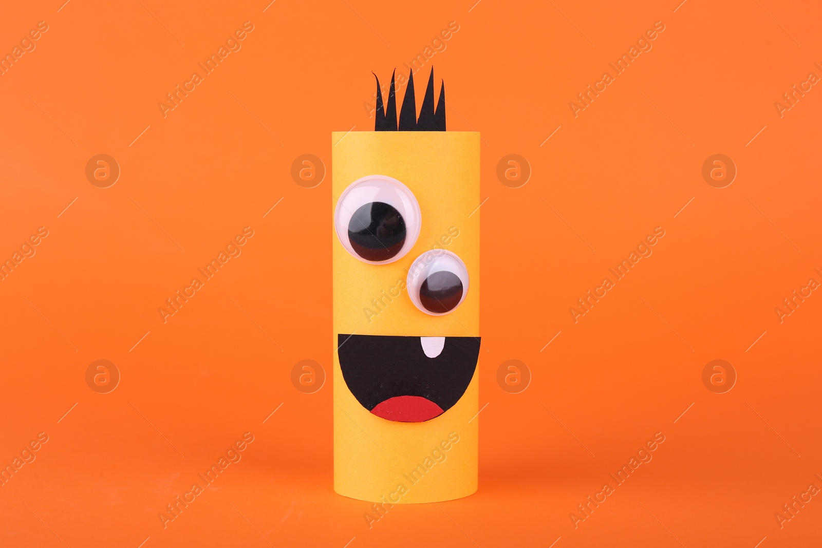 Photo of Spooky paper monster on orange background. Handmade Halloween decoration