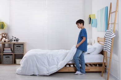 Boy changing bed linens in children room