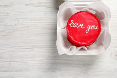 Photo of Bento cake with Love You text in takeaway box on white wooden table, top view. Space for text. St. Valentine's day surprise