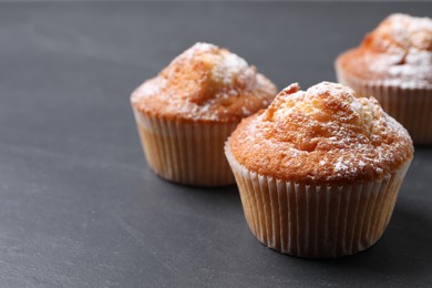 Photo of Delicious sweet muffins on black table, closeup. Space for text