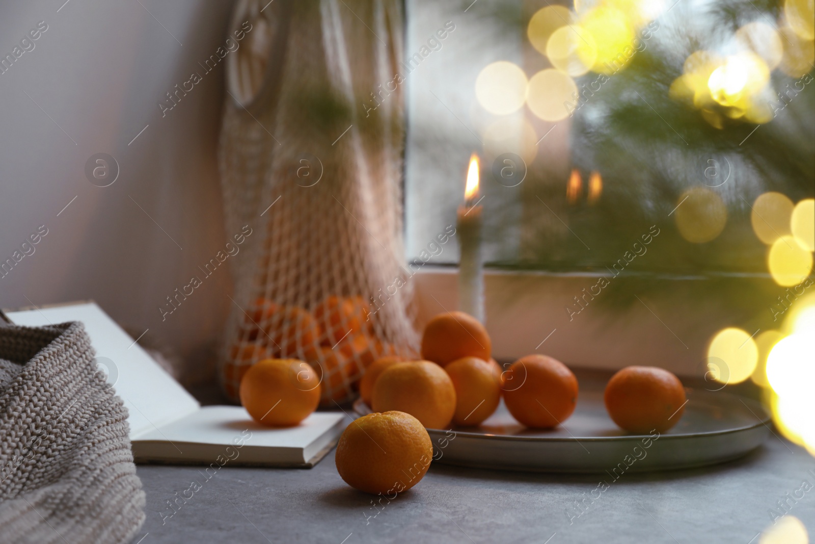 Photo of Fresh ripe tangerines and Christmas decor on grey table near window