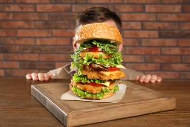 Man hiding behind huge burger on table