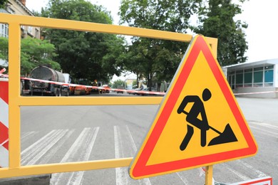 Photo of Barricade with road construction sign on city street, closeup. Repair works