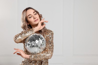 Photo of Beautiful woman in golden dress with disco ball posing on white background, space for text