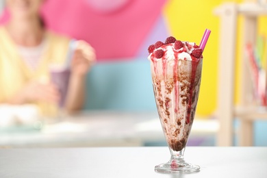 Photo of Tasty milk shake with topping on white table indoors. Space for text