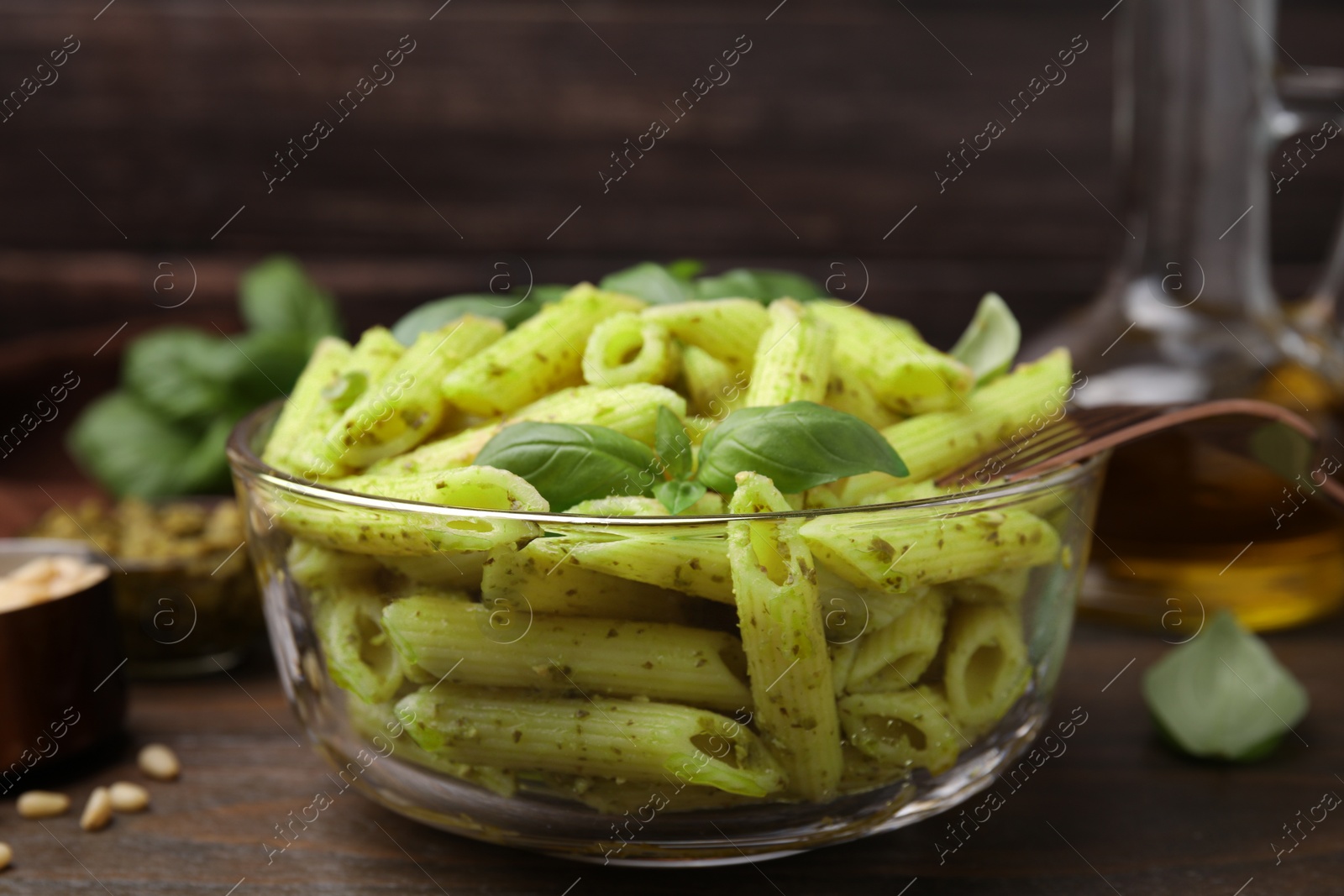 Photo of Delicious pasta with pesto sauce and basil on wooden table, closeup