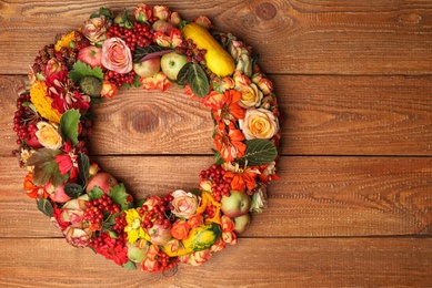 Beautiful autumnal wreath with flowers, berries and fruits on wooden background, top view. Space for text