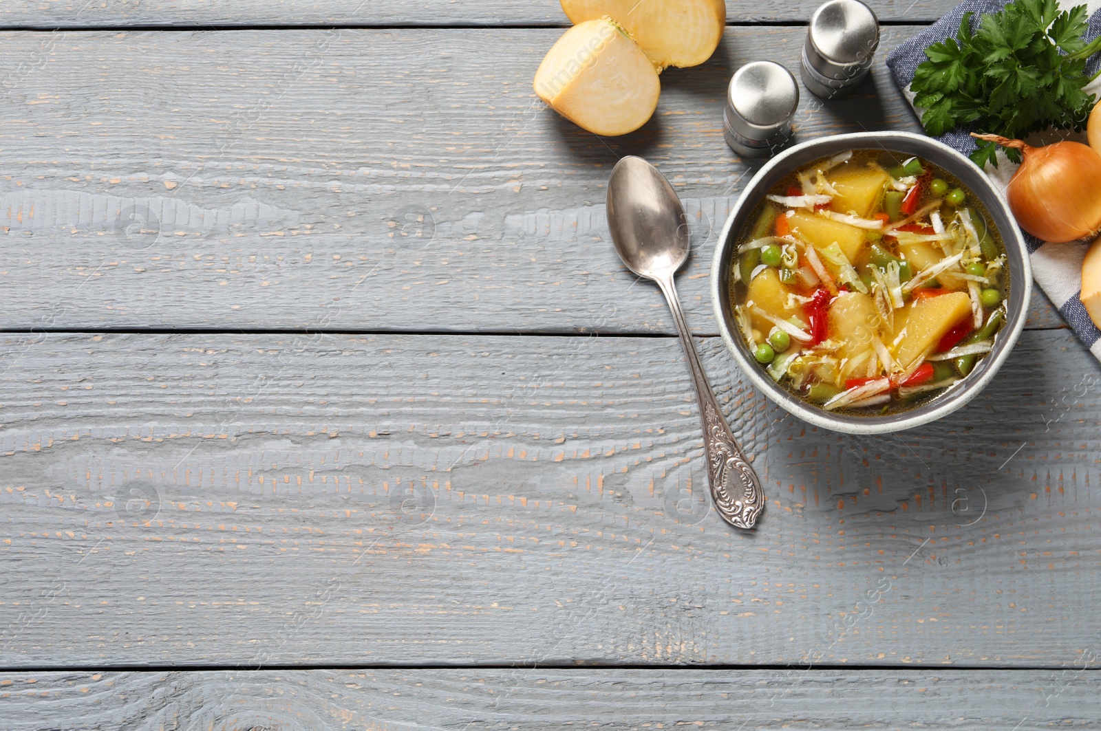 Photo of Bowl of delicious turnip soup served on grey wooden table, flat lay. Space for text