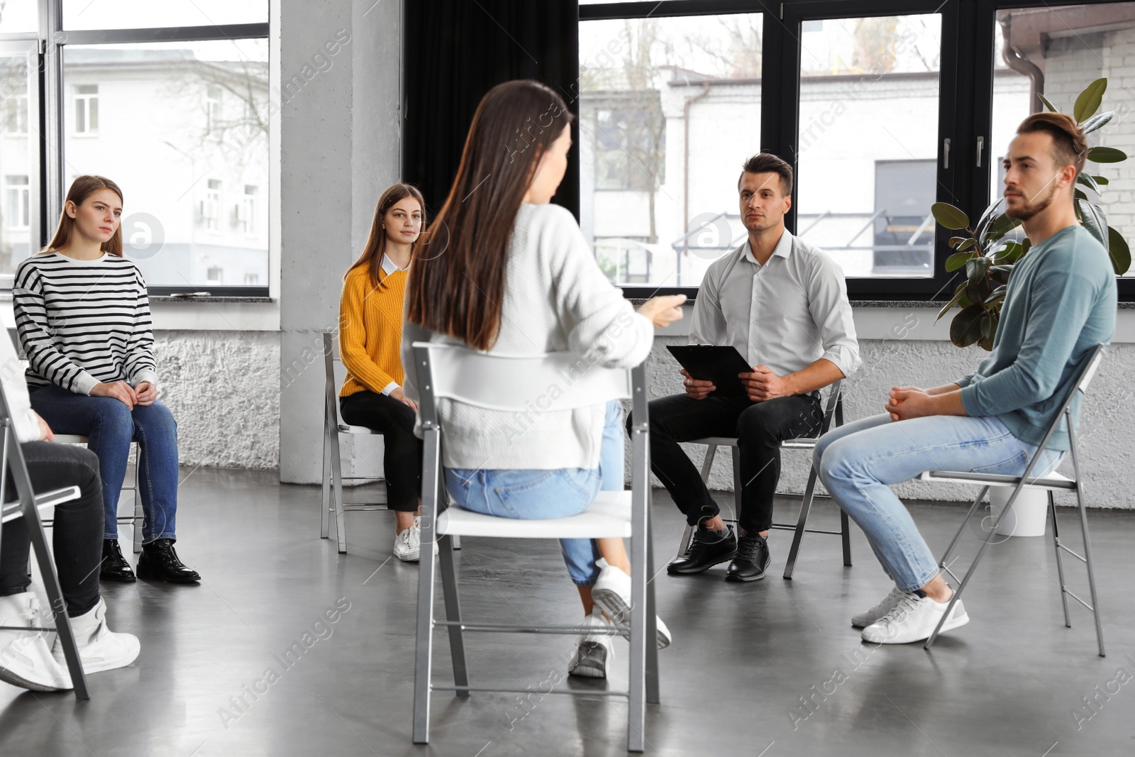 Photo of Psychotherapist working with patients in group therapy session indoors