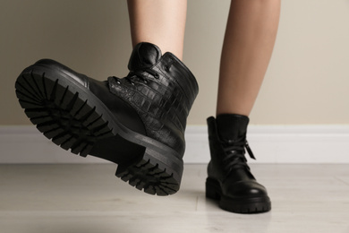 Photo of Woman wearing stylish boots near beige wall indoors, closeup