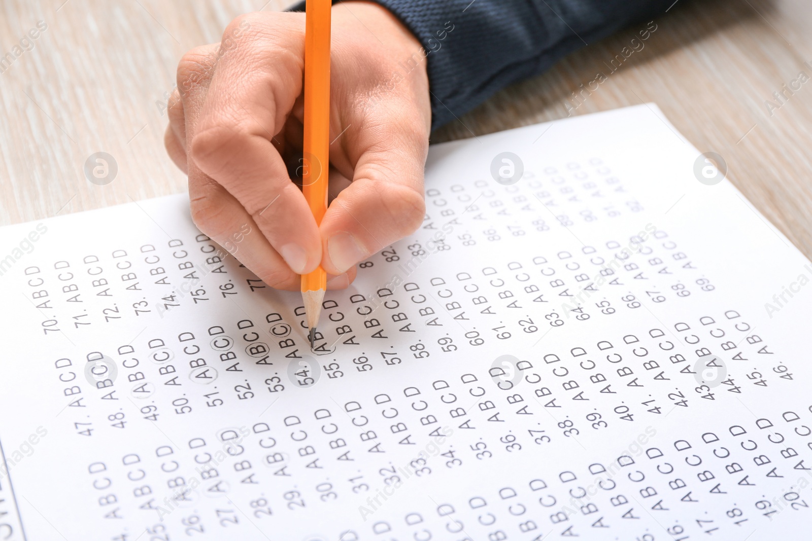 Photo of Student filling answer sheet at table, closeup