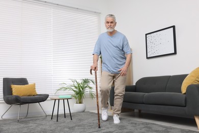 Photo of Senior man with walking cane at home