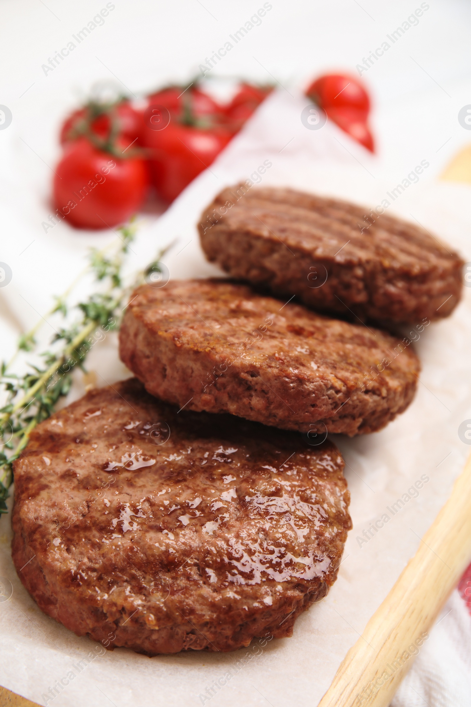 Photo of Wooden board with tasty grilled hamburger patties on table, closeup