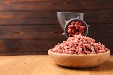 Photo of Manual meat grinder with beef mince on wooden table, space for text