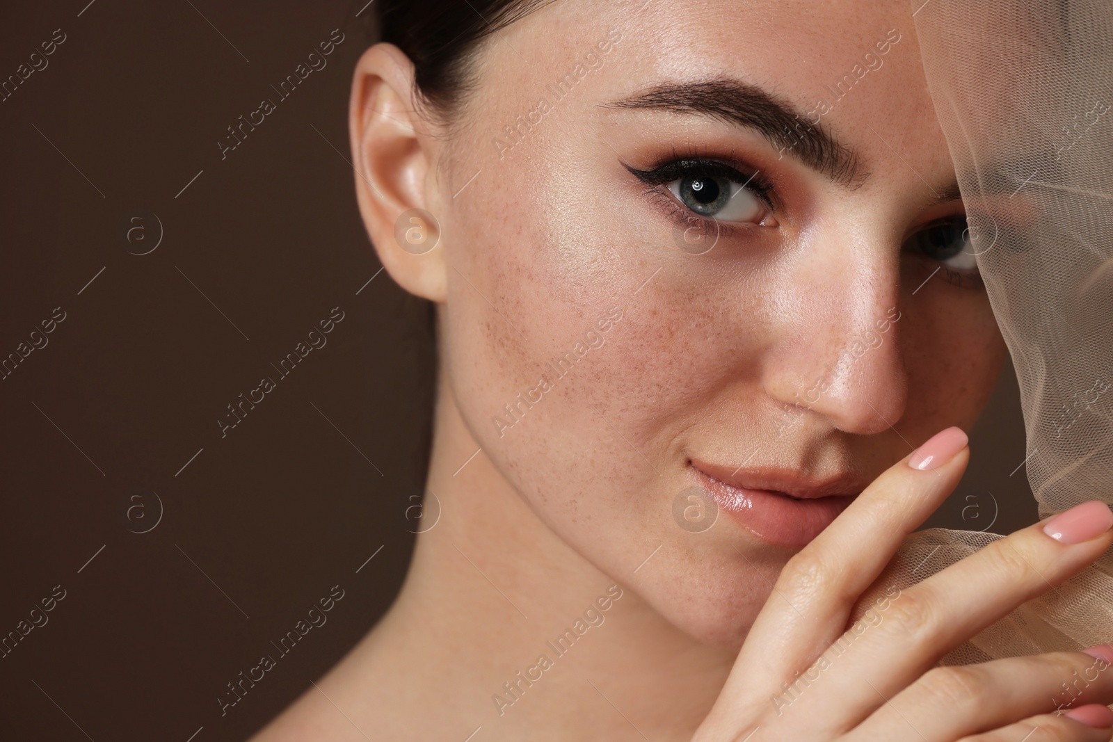 Photo of Fashionable portrait of beautiful woman with fake freckles on brown background, closeup. Space for text