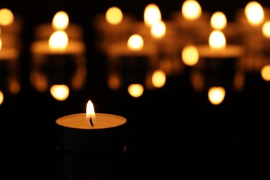 Photo of Burning candle on surface in darkness, closeup. Space for text