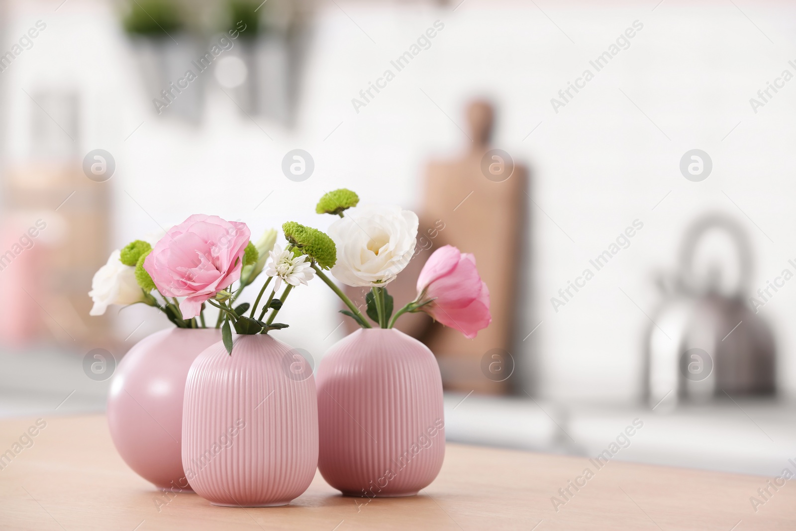 Photo of Vases with beautiful flowers on table in kitchen interior. Space for text