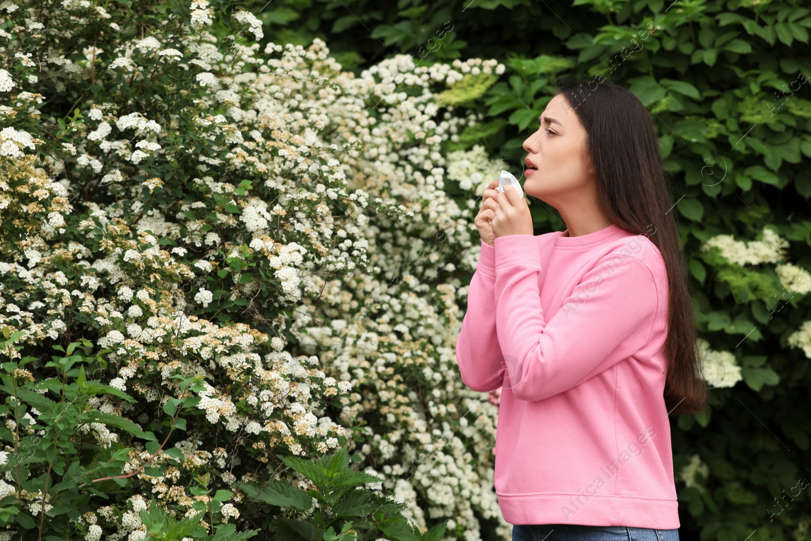 Photo of Woman suffering from seasonal pollen allergy near blossoming tree on spring day