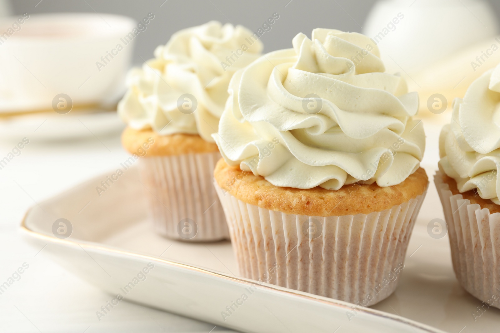 Photo of Tasty cupcakes with vanilla cream on white wooden table, closeup