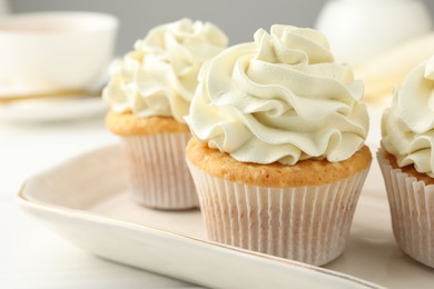 Photo of Tasty cupcakes with vanilla cream on white wooden table, closeup