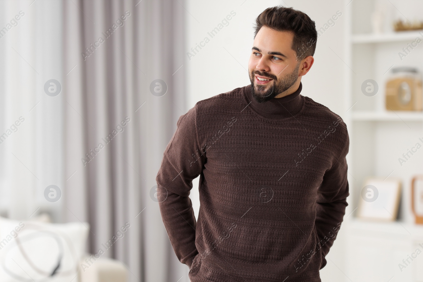 Photo of Happy man in stylish sweater at home, space for text