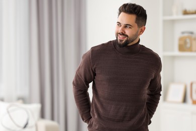 Photo of Happy man in stylish sweater at home, space for text