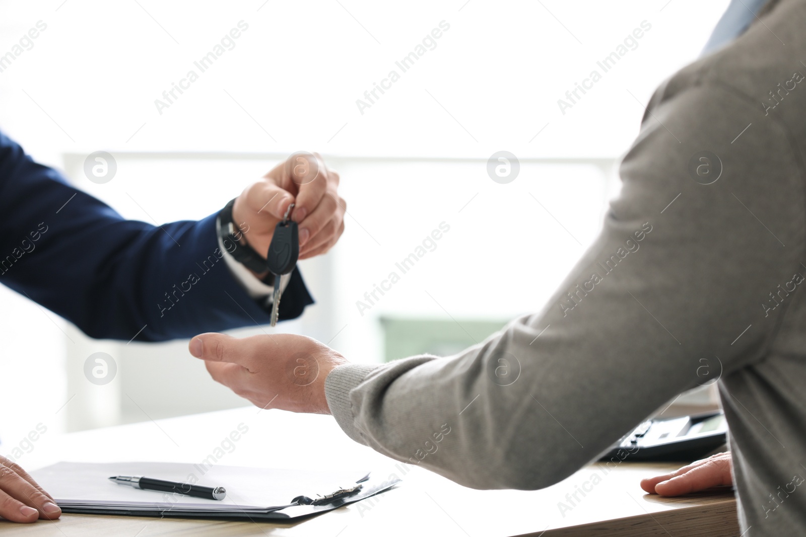 Photo of Salesman giving key to customer in office, closeup. Buying new car