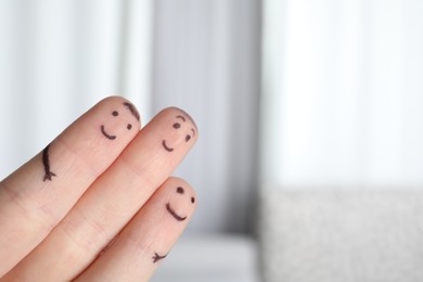 Photo of Three fingers with drawings of happy faces on blurred background, space for text