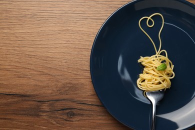 Photo of Heart made with spaghetti and fork on wooden table, top view. Space for text