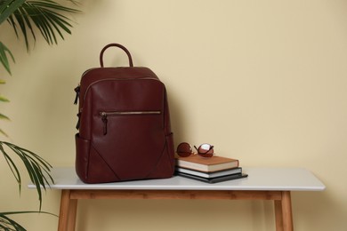 Stylish urban backpack, books and sunglasses on console table