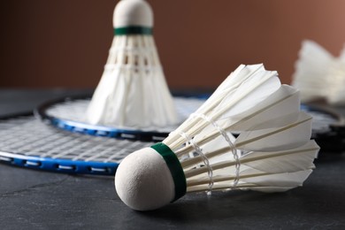 Photo of Feather badminton shuttlecocks and racket on grey table against brown background, closeup