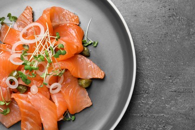 Photo of Salmon carpaccio with capers, onion and microgreens on grey table, top view