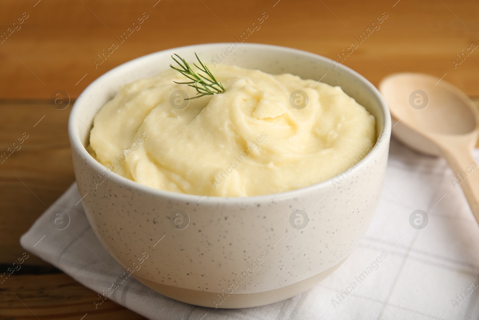 Photo of Freshly cooked homemade mashed potatoes, napkin and spoon on wooden table, closeup