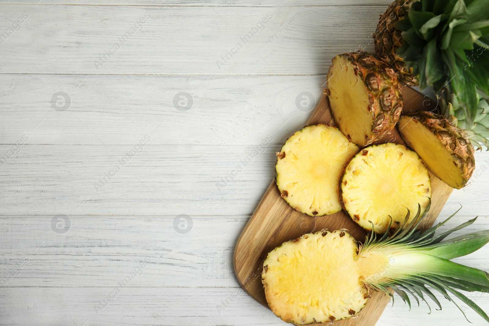 Photo of Slices of fresh pineapple on white wooden table, flat lay. Space for text