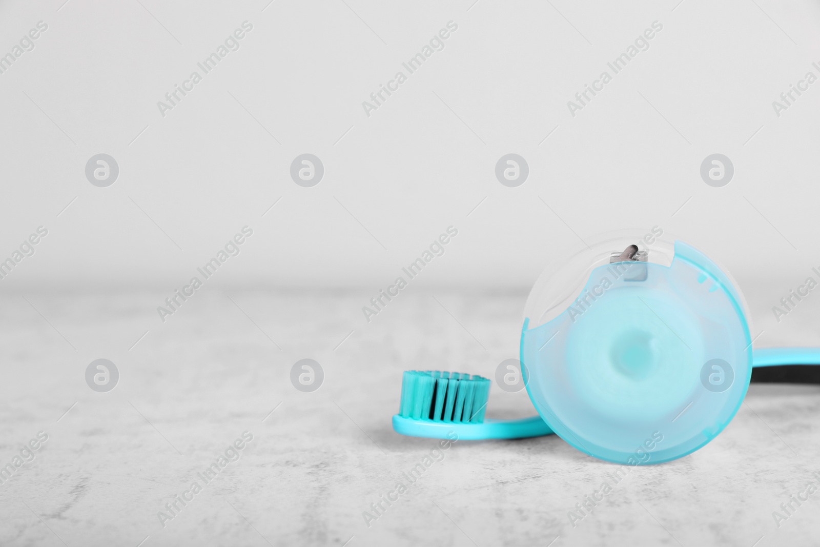 Photo of Container with dental floss and toothbrush on light grey textured table. Space for text