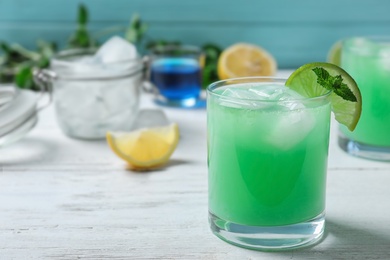 Glass of delicious cocktail with ice on white wooden table. Space for text