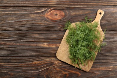 Board with fresh green dill on wooden table, top view. Space for text
