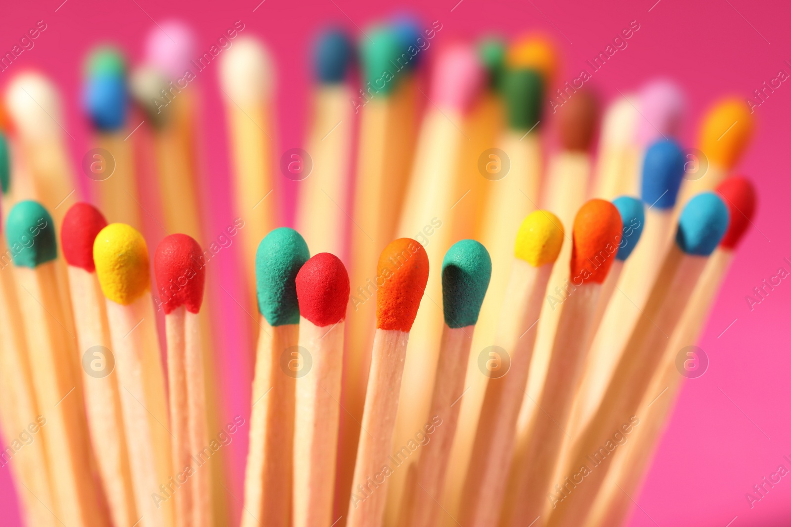 Photo of Matches with colorful heads on pink background, closeup