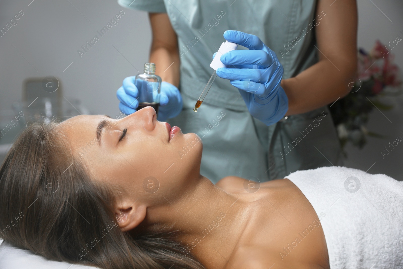 Photo of Cosmetologist applying serum on client's face in salon