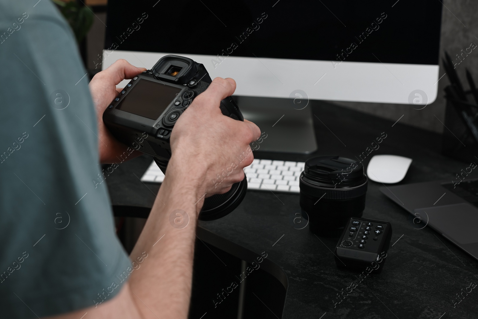 Photo of Photographer holding camera near dark table, closeup