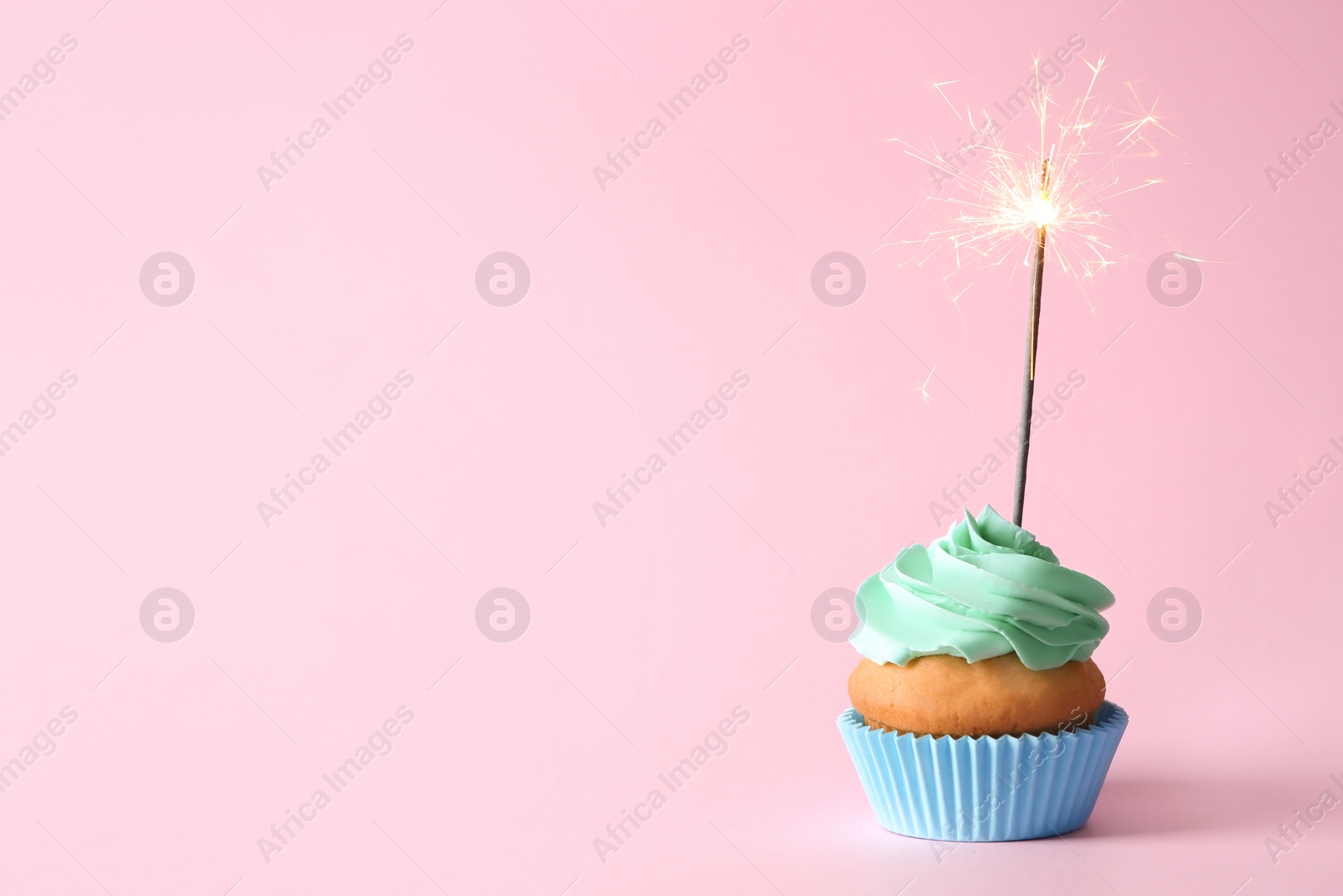 Photo of Delicious birthday cupcake with burning sparkler and space for text on color background